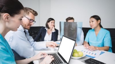 Doctors discussing over laptop in meeting at conference room